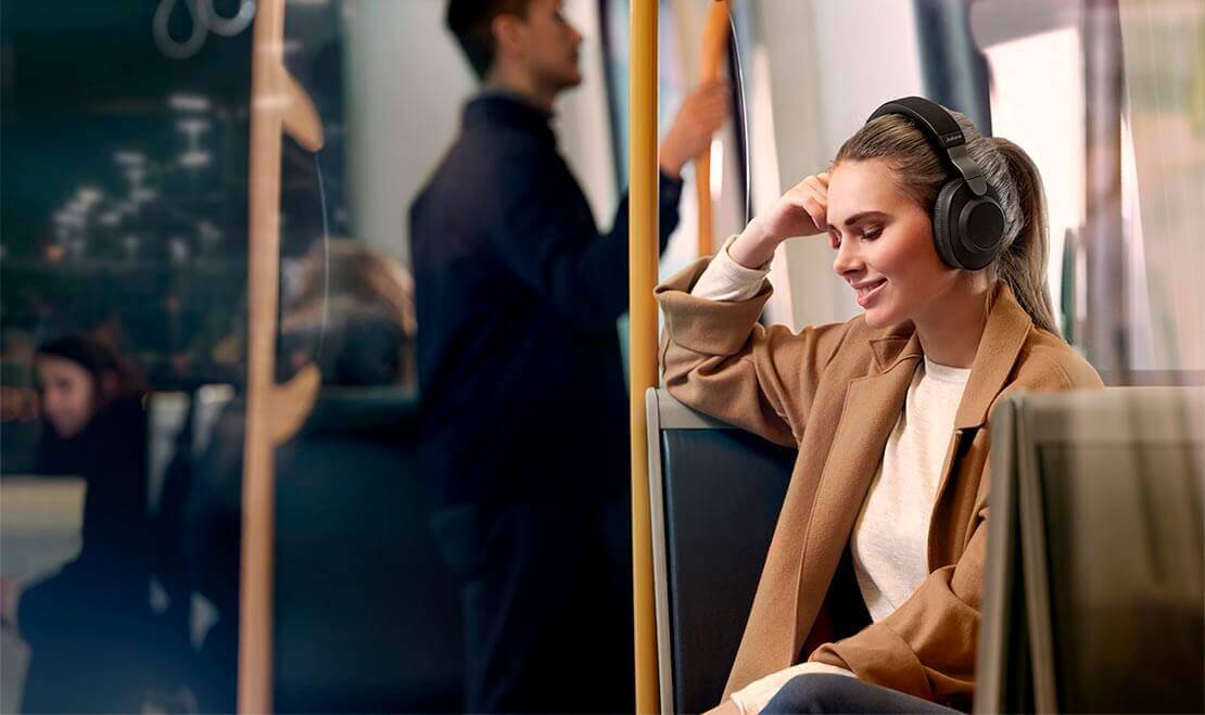 Woman using Jabra Elite 85h wireless headphones in public transportation